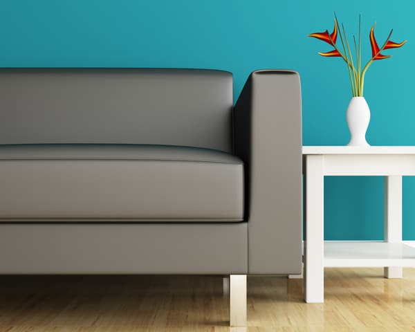 iStock Credit: sayhmog A close-up of a modern gray sofa against a teal wall